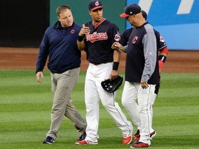 In this Tuesday, Aug. 8, 2017 photo, Cleveland Indians outfielder Michael Brantley, middle, walks off the field with a trainer, left, and manager Terry Francona in Cleveland. (AP Photo/Tony Dejak)