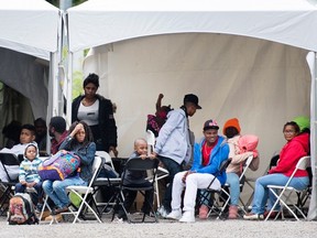 Asylum seekers wait to be transported to a processing centre after entering Canada illegally from the United States at Roxham road in Hemmingford, Que., Wednesday, August 9, 2017. THE CANADIAN PRESS/Graham Hughes
