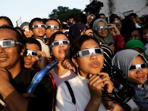 In this Wednesday, March 9, 2016 file photo, people wearing protective glasses look up at the sun to watch a solar eclipse in Jakarta, Indonesia. Doctors say not to look at the sun without eclipse glasses or other certified filters except during the two minutes or so when the moon completely blots out the sun, called totality. That’s the only time it’s safe to view the eclipse without protection. When totality is ending, then it’s time to put them back on. (AP Photo/Dita Alangkara)