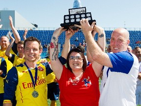 (left to right) Matthew Harris, Cst. Daniel Woodall's widow Claire Woodall, and Bruce McGregor hold up the Woodall Cup at Clarke Stadium, in Edmonton Alta. on Sunday July 26, 2015. The charity soccer game pitted a team of British ex-pats against Edmonton Police Service officers. The third edition of the game takes place Friday (3:30 p.m.) at Clarke Stadium.