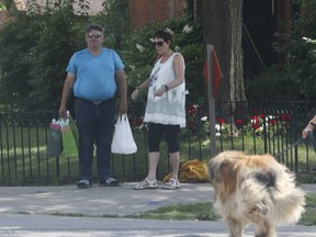 A man who identified himself as the site manager of a watermain replacement project on Bedford Rd., south of Davenport Rd., stands chatting with a woman at the southeast corner of Bedford Rd. and Bernard Ave. (JACK BOLAND, Toronto Sun)