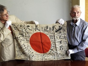 In this Monday, Aug. 7, 2017 photo, Second World War veteran Marvin Strombo (right) and Obon Society executive director Rex Ziak hold up a Japanese flag with names written on it in Portland, Ore. Strombo recovered the flag from a dead Japanese soldier in the Pacific more than 70 years ago and now, at age 93, will return the flag to the Japanese man's surviving siblings. (Don Ryan/AP Photo)