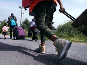 Wearing her gold high-stop sneakers, Lena Gunja, 10, originally from Congo and who had been living in Portland, Maine, follows her family as they approach an unofficial border crossing with Quebec while walking down Roxham Road in Champlain, N.Y., on Monday, Aug. 7, 2017. (Charles Krupa/AP Photo)