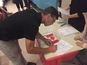 Brian Amble signs his citizenship forms at the ceremony at the Pearl of the Orient Philippine pavilion.