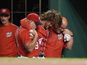 Washington Nationals' Bryce Harper, center, is helped in the dugout after he was injured during the first inning of the team's baseball game against the San Francisco Giants, Saturday, Aug. 12, 2017, in Washington. (AP Photo/Nick Wass)