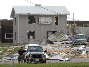 A firefighter walks past damage caused by a tornado in Durham, Ont., last August. (POSTMEDIA NETWORK),