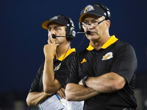 Hamilton Tiger-Cats head coach Kent Austin, left, and new defensive coordinator Phillip Lolley watch a play develop against the Winnipeg Blue Bombers in first-half CFL action in Hamilton, Ont., Saturday, August 12, 2017. (THE CANADIAN PRESS/Aaron Lynett)