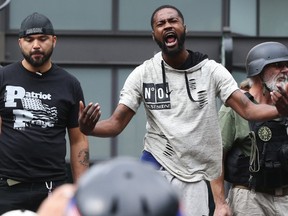 Conservative Joey Gibson, left, looks on after Black Lives Matter protester Arthur Ford, centre, took the stage during a pro-Trump rally at Westlake Park, Sunday, Aug. 13, 2017, in Seattle. (Ken Lambert/The Seattle Times via AP)