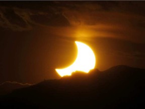 In this May 20, 2012, file photo, the annular solar eclipse is seen as the sun sets behind the Rocky Mountains from downtown Denver. DAVID ZALUBOWSKI / AP