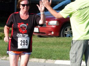 Wallaceburg's Ellen Bourhis gets a high-five from volunteer Ron Ameloot just before she finishes during the WAMBO River Run on Saturday, August 12.