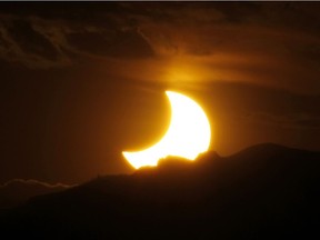 In this May 20, 2012, file photo, the annular solar eclipse is seen as the sun sets behind the Rocky Mountains from downtown Denver. Destinations are hosting festivals, hotels are selling out and travelers are planning trips for the total solar eclipse that will be visible coast to coast on Aug. 21, 2017. A narrow path of the United States 60 to 70 miles wide from Oregon to South Carolina will experience total darkness, also known as totality. (AP Photo/David Zalubowski, File)