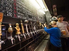 In this July 21, 2017 photo, waiters pour craft beer at the Rule Taproom pub in Moscow, Russia. Pint by frothy pint, a hoppy revolution is brewing in Russia. A new generation of craft beer brewers began sprouting in the vodka capital of the world as foreign beers got too expensive and beer-drinkers started looking for alternatives to mass-produced lagers. (AP Photo/Alexander Zemlianichenko)