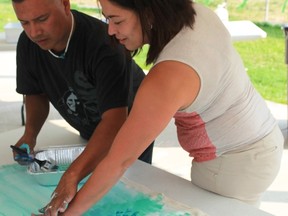 Aamjiwnaang artist John Williams helps Elizabeth Cronk place her paint-splattered left hand on his recently commenced mural, Destined For Greatness, on August 8th.
CARL HNATYSHYN/SARNIA THIS WEEK
CARL HNATYSHYN/SARNIA THIS WEEK