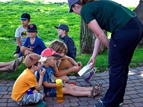 Sarah Downey, environmental educator for Alberta Parks, shows young members of the audience a display containing different types of bees during a presentation in front of the library on Aug. 11. | Stephanie Hagenaars photo / Pincher Creek Echo