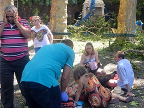 People attend to an injured person at the scene where a tree fell on a large crowd on the outskirts of Funchal, the capital of Madeira island, Portugal, Tuesday, Aug. 15, 2017. Portuguese authorities say a tree that fell during a popular religious festival on the island of Madeira killed at least 12 people and more than 50 others were injured in the accident near the island capital of Funchal. The tree fell while a large crowd was gathered as part of a Nossa Senhora do Monte festival. (ASPRESS via AP)