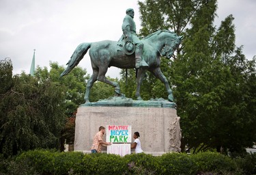 Tom Lever, 28, and Aaliyah Jones, 38, both of Charlottesville, put up a sign that says "Heather Heyer Park" at the base of the Confederate general Robert E. Lee monument in Emancipation Park Tuesday, Aug. 15 in Charlottesville, Va.  Alex Fields Jr., is charged with second-degree murder and other counts after authorities say he rammed his car into a crowd of counterprotesters, including Heyer, Saturday, where a white supremacist rally took place.  (AP Photo/Julia Rendleman)