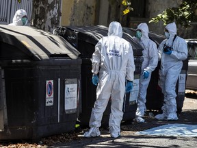 Italian police officers and forensic experts inspect a trash bin in which were found parts of human body in Rome, Wednesday, Aug. 16, 2017. Police in Rome say they are investigating a suspected murder after a pair of hacked-off legs, apparently of a woman, was found in a trash bin on an upscale street in the Italian capital, and a head and torso found in trash elsewhere. Police officials say they were questioning the brother of the victim Wednesday. (Angelo Carconi/ANSA via AP)