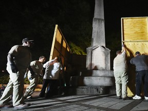 Birmingham city workers use plywood panels to cover the Confederate Monument in Linn Park, in Birmingham, Ala., Tuesday night, Aug. 15, 2017, on orders from Mayor William Bell. (Joe Songer /AL.com via AP)