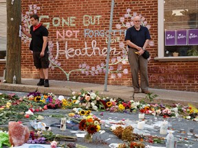 Jason Charter, left, of Washington, stands at a memorial on Aug. 16, 2017, in Charlottesville, Va., at the site where Heather Heyer was killed during a white nationalist rally. Charter was at the scene when a car rammed into a crowd of people protesting the rally. (AP Photo/Evan Vucci)