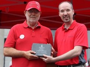 Kingston Mayor Bryan Paterson, right, presents the First Capital Distinguished Citizen Award to longtime rowing coach John Armitage at a civic ceremony in front of City Hall on July 1. (Steph Crosier/The Whig-Standard)