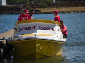 Honolulu Fire Department search and rescue members sit on a docked boat at a boat harbor, Wednesday, Aug. 16, 2017, in Haleiwa, Hawaii. An Army helicopter with five on board crashed several miles off Oahu's North Shore late Tuesday. Rescue crews are searching the waters early Wednesday. (AP Photo/Marco Garcia)