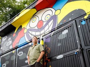 Fringe Theatre Adventures artistic director Murray Utas poses in front of artwork created for the Fringe outside the Arts Barns in Edmonton on Monday, July 31, 2017. (Codie McLachlan/Postmedia)