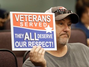 Steve Damron, 50, of Spring Hill, Fla., holds up a sign during a Hillsborough County Commission meeting about possible moving of a Confederate statue Wednesday, Aug. 16, 2017, in Tampa, Fla. Damron said the President Donald Trump handled the Charlottesville situation well, and he agreed with Trump that "both sides" were to blame. (AP Photo/Chris O'Meara)