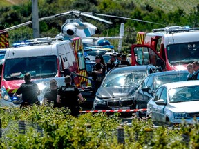 Police officers and emergency workers stand next to a damaged BMW car with a broken windscreen, after the police arrested a suspect on the A16 motorway, near Marquise, northern France, on August 9, 2017.