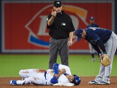 Toronto Blue Jays shortstop Ryan Goins (17) lies in pain after being tagged out and stepped on by Tampa Bay Rays shortstop Daniel Robertson (29) during sixth inning AL baseball action in Toronto on Wednesday, August 16, 2017. (Nathan Denette/THE CANADIAN PRESS)