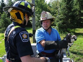 Landowner Dave Craig holds a juvenile osprey as he and Firefighter Byron McNeely prepare to lift it back into its nest Thursday morning. DANIELLE CARDINAL / OTTAWA FIRE SERVICE