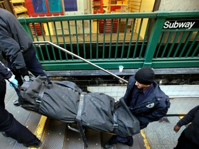 In this Jan. 22, 2013 file photo, a police officer and medical examiner personnel carry a body out of the Times Square subway station in New York after witnesses told police that the man who died jumped into the path of an oncoming train. (AP Photo/Seth Wenig, File)