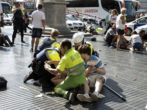 Medics and police tend to injured people near the scene of a terrorist attack in the Las Ramblas area on August 17, 2017 in Barcelona, Spain. Officials say 13 people are confirmed dead and at least 100 injured after a van plowed into people in the Las Ramblas area of the city this afternoon. (Photo by Nicolas Carvalho Ochoa/Getty Images)