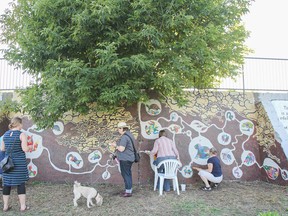 People add their own touches to the community mural at the On the Wall street art festival in August 2014. This year’s event starts Monday. (Whig-Standard file photo)