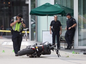 A police officer photographs a motorcycle after a female stunt driver working on the movie "Deadpool 2" died after a crash on set, in Vancouver, B.C., on Monday August 14, 2017. THE CANADIAN PRESS/Darryl Dyck