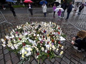 A woman places a candle by floral tributes for the victims of an attack at Turku Market Square in Turku, Finland, Saturday, Aug. 19, 2017. A suspect detained for allegedly stabbing two people to death in a wild knife attack in the western Finnish city is being investigated for murder with possible terrorist intent, police said Saturday. (Vesa Moilanen/Lehtikuva via AP)