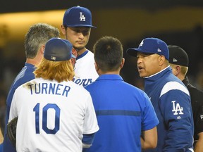 Justin Turner #10 listens as manager Dave Roberts #30 of the Los Angeles Dodgers talks to team trainers as they decide to pull pitcher Yu Darvish #21 at the start of the seventh inning of the game against the Chicago White Sox at Dodger Stadium on August 16, 2017 in Los Angeles, California. (Jayne Kamin-Oncea/Getty Images)