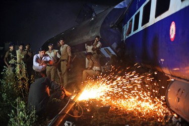 Indian police watch as rescue work is in progress near the upturned coaches of the Kalinga-Utkal Express after an accident near Khatauli, in the northern Indian state of Uttar Pradesh, India, Sunday, Aug. 20, 2017. (AP Photo/Altaf Qadri)