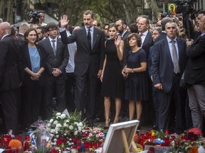 Spain's King Felipe and Queen Letizia wave to the crowd after paying respects at a memorial tribute of flowers, messages and candles to the van attack victims at Las Ramblas promenade, Barcelona, Spain, Saturday, Aug. 19, 2017. (Santi Palacios/AP Photo)