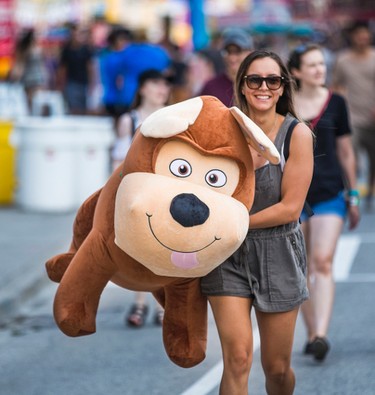 Cristina Sa carrying a giant stuffed dog, won by her boyfriend at Frank Laconis (not pictured) at the annual CNE in Toronto, Ont. on Sunday August 20, 2017. Laconis won the dog with the shooting game with the paper target.  Ernest Doroszuk/Toronto Sun/Postmedia Network