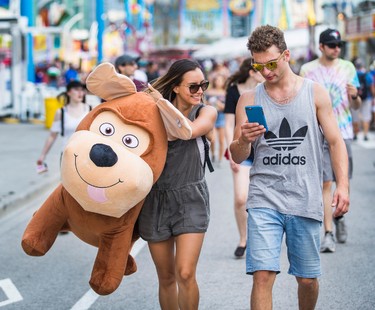 Cristina Sa carrying a giant stuffed dog, won by her boyfriend at Frank Laconis (right) at the annual CNE in Toronto, Ont. on Sunday August 20, 2017. Laconis won the dog with the shooting game with the paper target.  Ernest Doroszuk/Toronto Sun/Postmedia Network