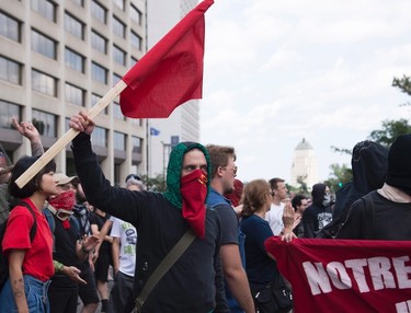 A masked man holds a communist flag during an anti-racism demonstration, in Quebec City on Sunday, Aug. 20, 2017. THE CANADIAN PRESS/Jacques Boissinot