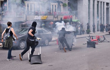 A protester prepares to throw a bottle while another rolls a smouldering dumpster towards police lines during an anti-racism demonstration, in Quebec City on Sunday, Aug. 20, 2017. THE CANADIAN PRESS/Jacques Boissinot
