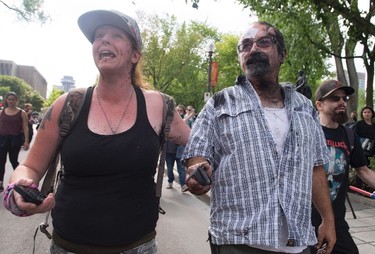 Eric Roy gets help from an unidentified friend, left, after he was attacked by a group of people during an anti-racism demonstration, in Quebec City on Sunday, Aug. 20, 2017. THE CANADIAN PRESS/Jacques Boissinot