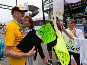 Roger MacMillan hugs his wife, Lesley, after crossing the finish line with his grandchildren at the Edmonton Marathon on Sunday August 20, 2017. The 79 year old runner completed his 100th marathon. Greg Southam / Postmedia