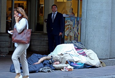 Councillor Giorgio Mammoliti stands beside homeless people sleeping on the streets outside a Tim Hortons across where a safe injection site is set to open near Yonge/Dundas Sq. in Toronto on Monday August 21, 2017. (Dave Abel/Toronto Sun)