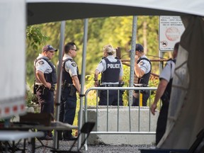 RCMP officers wait for the arrival of asylum seekers crossing the border into Canada from the United States at a police checkpoint close to the Canada-U.S. border near Hemmingford, Que., on Thursday, August 3, 2017. THE CANADIAN PRESS/Paul Chiasson
