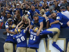 Winnipeg Blue Bomber players jump into the north end zone stands after a touchdown run from quarterback Dan LeFevour against the Edmonton Eskimos during CFL action in Winnipeg on Thurs., Aug. 17, 2017. Kevin King/Winnipeg Sun/Postmedia Network ORG