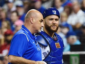 Toronto Blue Jays catcher Russell Martin (right) walks back to the dugout with an injury with trainer George Poulis on August 11, 2017. Martin was placed on the disabled list the next day. (NATHAN DENETTE/The Canadian Press)