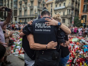 A policeman hugs a boy and his family that he helped during the terrorist attack, at a memorial to the victims on Las Ramblas, Barcelona, Spain, Monday Aug. 21, 2017. (AP Photo/Santi Palacios)