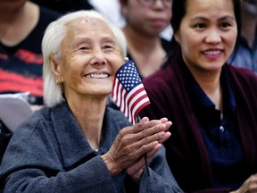 Hong Inh waves an American flag and smiles after taking the oath to become a United States citizen at the Los Angeles Convention Center, Tuesday, Aug. 22, 2017. (AP Photo/Richard Vogel)